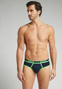 Marina shorts med gröna accenter och logotyp, tillverkade av ett mjukt tyg. Har en åtsittande passform och en kontrasterande midja.