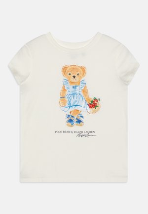 Biała koszula z krótkim rękawem z nadrukiem misia w niebieskiej sukience i butach, trzymającego koszyk truskawek, z logo Ralph Lauren poniżej.