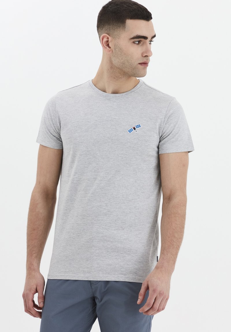 Tricou gri din bumbac cu guler rotund, prezentând o mică grafică albastră a unui satelit pe partea stângă a pieptului. Mâneci scurte, croială casual.