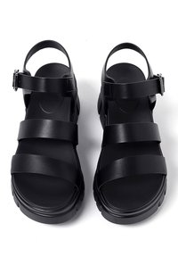 Sandali platform neri con tre cinturini larghi, una cinghia alla caviglia con fibbia e una suola in gomma testurizzata. Finitura liscia e design moderno.