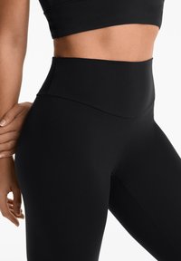 Fekete, magas derekú leggings sima, rugalmas anyagból. Zökkenőmentes derékrész és karcsú fazon jellemzi, amely a kényelmet és teljesítményt szolgálja.