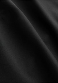 Tissu noir avec une texture lisse et mate, présentant un drapé subtil et des plis. Aucun motif ni accent visible.