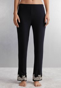 Zwarte loungebroek van zachte stof, met een bloemenkantpatroon aan de zoom. Elastische tailleband voor comfort.