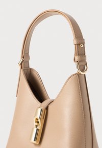 Beige Lederhandtasche mit strukturierter Form, einem markanten goldenen Hardware-Verschluss und einer glatten Textur auf dem Körper und dem Tragegurt.