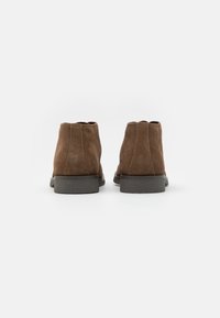 Brown suede ankle boots with short shafts, rounded toes, and textured rubber soles, featuring stitched side seams and minimal design.