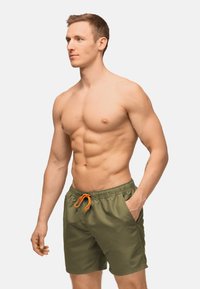Costumi da bagno verde oliva con vita elastica, cordino arancione e tasche laterali. Realizzati in un materiale leggero e liscio.