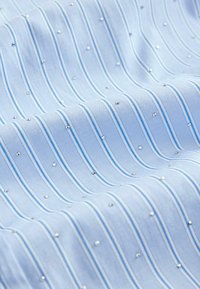 Tessuto azzurro chiaro con strisce orizzontali e piccole paillettes argentate, caratterizzato da una texture liscia e una lucentezza sottile.