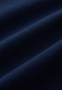 Tela de algodón azul marino con una textura suave, que exhibe un sutil ribeteado y pliegues que crean profundidad y dimensión.