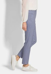 Blauwe geprinte broek met een geometrisch patroon, gemaakt van lichtgewicht stof, gecombineerd met witte sneakers. Afgeknotte enkel lengte.