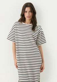 Robe t-shirt oversize rayée noir et blanc en coton doux, avec des manches courtes, un col rond et une coupe décontractée.