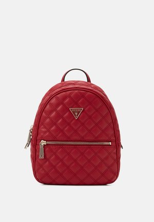 Sac à dos en cuir rouge matelassé avec poche zippée avant, poignée supérieure et plaque logo métallique sur fond uni.