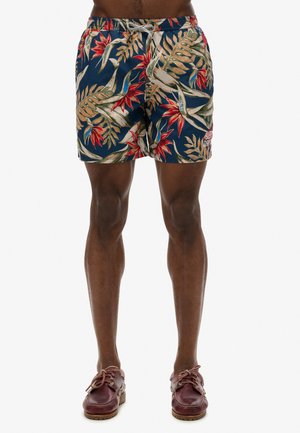 Bañadores estampados con un fondo azul marino y follaje tropical con flores rojas. Cintura elástica con cordón ajustable. Longitud hasta medio muslo.