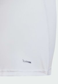 Beli prilegli športni šort, narejen iz lahkega materiala, z gladko teksturo in majhnim logotipom "climaCool" blizu roba.