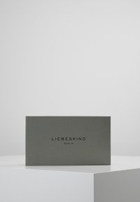 Szare prostokątne pudełko o fakturowanej powierzchni, z czarną nazwą marki "LIEBESKIND BERLIN" na środku z przodu.