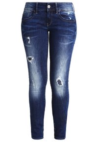 Jeans de denim ajustados en azul oscuro con parches desgastados y un ligero desvanecimiento. Presenta un estilo de cinco bolsillos y un cierre de botón.