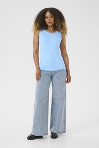 Débardeur bleu clair à côtes avec des bords festonnés, assorti à un jean large en denim clair et à des chaussures à plateforme noires.