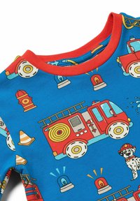 Camiseta de pijama de algodón con un fondo azul decorado con un camión de bomberos, un dálmata y símbolos de emergencia en rojo, amarillo y negro, todo en una textura suave.