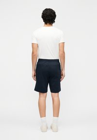 Námornícky modré basketbalové šortky s elastickým pásom, v kombinácii s bielym tričkom s krátkym rukávom, zobrazené zozadu.