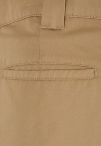 Beige cotton fabric with a smooth texture, featuring a double-stitched back pocket and subtle vertical pattern. Minimalist design.
