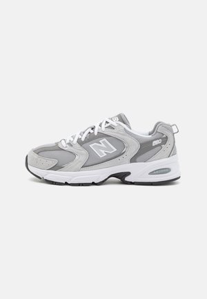 Szare i białe sneakersy New Balance 680 z siateczkowymi i zamszowymi panelami, białymi sznurówkami oraz grubą białą podeszwą z czarnymi akcentami bieżnika.