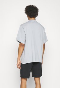 Light gray oversized T-shirt with short sleeves and a round neck, made of soft cotton material, paired with black shorts.