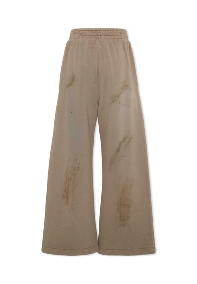 Pantaloni beige a gamba larga con fascia elastica in vita, caratterizzati da molteplici macchie scure sbiadite e aloni su entrambe le gambe.