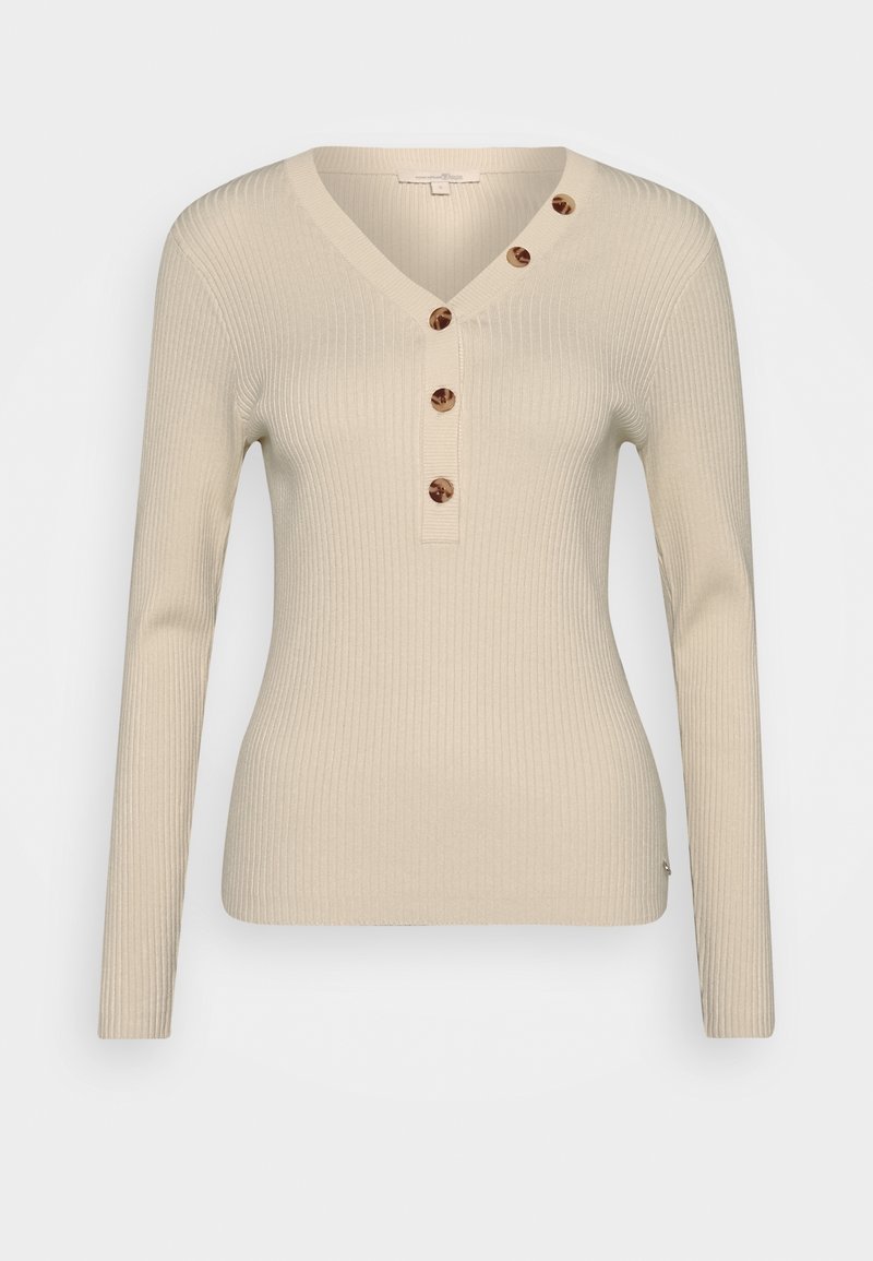 Haut beige à manches longues côtelé avec un col en V et une patte de boutonnage dotée de quatre boutons ronds marron. Tissu doux avec une coupe ajustée.