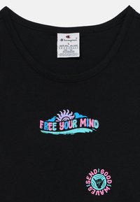 T-shirt nera in cotone con grafica colorata che riporta il testo "LIBERA LA TUA MENTE" accompagnato da un design di sole e onda e l'emblema "INVIA BUONE ENERGIE".