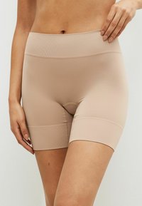 Beige nauwsluitende shorts met een hoge taille, gemaakt van ribbelstretchmateriaal. De shorts hebben een naadloos ontwerp en hebben een lengte tot halverwege de dij.
