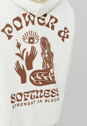 Sweat à capuche blanc avec un motif marron représentant une femme sans visage entourée de feuilles, de mains, d'un œil, et le texte « Pouvoir & Douceur Force en épanouissement ».