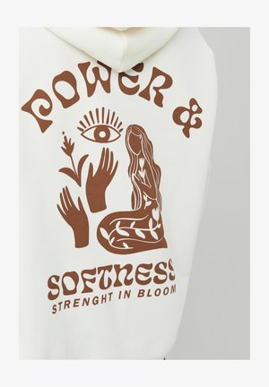 Sweat à capuche blanc avec un motif marron représentant une femme sans visage entourée de feuilles, de mains, d'un œil, et le texte « Pouvoir & Douceur Force en épanouissement ».