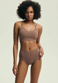 Brązowy prążkowany braletka z cienkimi ramiączkami, połączona z wysokim brązowym prążkowanym majtkami. Gładka tekstura, minimalistyczny design, brak widocznych elementów metalowych.