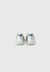 Pantofi sport argintii cu un design elegant, având suprafețe texturate, accente galbene contrastante și o talpă din cauciuc pentru aderență.