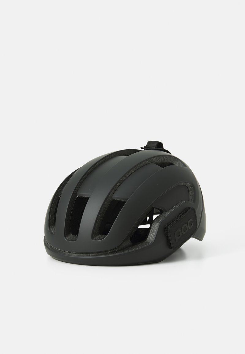 Black cycling helmet with a smooth matte finish, multiple ventilation slots, and a secure adjustment strap featuring a logo on the side.