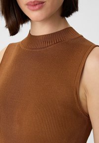 Bruine zonder mouwen top met een ribbelstructuur en een hoge, ronde halslijn, met zichtbare stiksels op de randen.