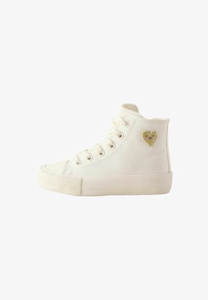 Zapatilla alta de lona blanca con puntera redonda, acento decorativo de corazón dorado, lados estructurados y suela de goma ligera.