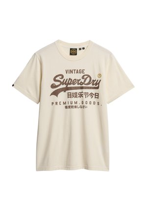 Kremowa bawełniana koszulka z krótkim rękawem, z dużym, brązowym tekstem i logo w stylu vintage z przodu. Okrągły dekolt, luźny krój.