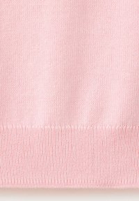 Gros plan d'un tissu tricoté rose clair avec une couture côtelée en bas, montrant la texture et les détails du motif en maille.