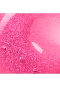 Surface liquide rose vif brillante avec de petites bulles et une texture scintillante sous réflexion de la lumière.