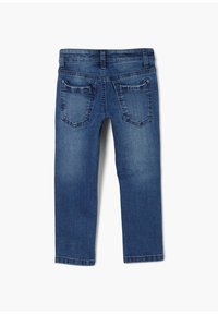 Džíny z denimu ve středně modré barvě s přiléhavým designem, které mají dvě zadní kapsy a jemné zesvětlení na nohavicích. Žádné přední kapsy nejsou viditelné.