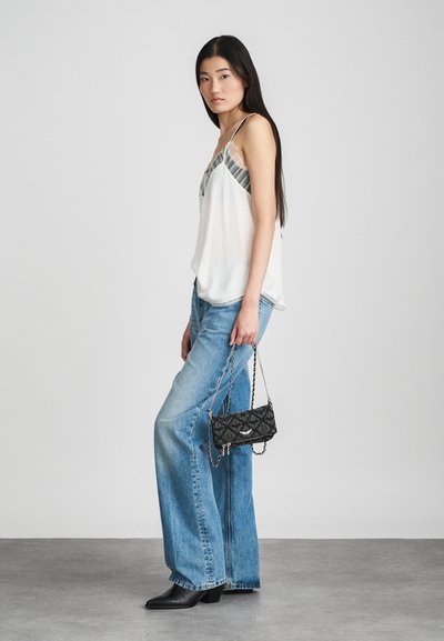 Hvid satin camisole med blonderdetaljer, parret med lyseblå brede jeans og en lille sort mønstret håndtaske med kædesnor.