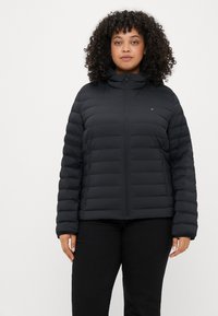 Schwarze Steppjacke mit durchgehendem Reißverschluss, hohem Kragen und horizontal gesteppten Paneelen. Verfügt über Logostickerei auf der Brust und elastische Bündchen.