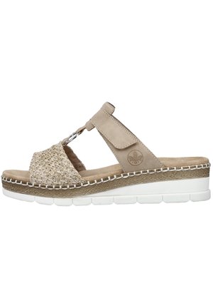 Beige sandal with a textured woven upper, featuring a T-strap design, cushioned footbed, and a white rubber sole with decorative stitching.