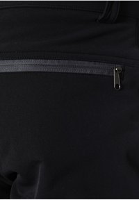 Svarta byxor med en slät textur som har en säker ficka med blixtlås på baksidan, framhävd av mörkgrått tyg.