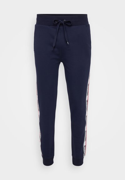 Marineblauwe trainingsbroek met een geribbelde tailleband en trekkoord. Bevat zijstrepen met logo-tekst in rood en wit, en taps toelopende boorden.