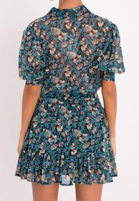 Kukkakuvioinen mekko läpikuultavasta, kevyestä kankaasta, jossa on tumma tausta sinisillä, beigenvärisillä ja vaaleanpunaisilla kukilla. Lyhyet puffihihat ja röyhelöreuna.