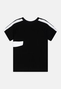 Svart kortärmad t-shirt med vita accentstriper på axlarna, rund hals, mjukt tyg och avslappnad passform, med en liten vit lappdetalj.