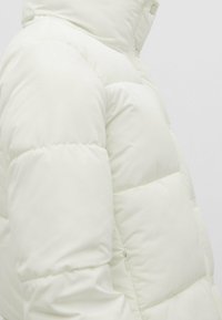 Dynejakke i off-white med quiltet design, hætte og sidelomme med lynlås; blødt, glat stof med en let blank finish.