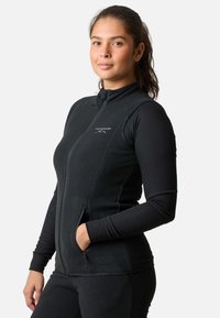 Sort fleece jakke med lynlås, ribbede lange ærmer, sidelommer og høj krave, med et diskret logo på brystet.