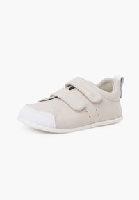 Scarpe beige per bambini con due cinturini in velcro, punta bianca e suola in gomma texturizzata. Parte superiore in pelle liscia con dettagli a perforazione.